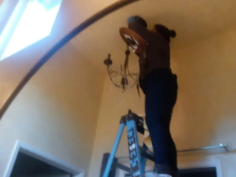 Electrician installing a chandelier in a Bastrop residence